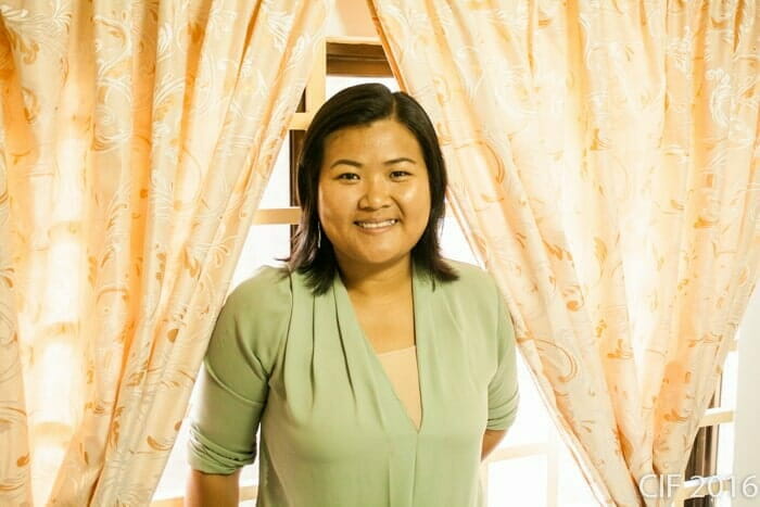 Leakena smiling, standing between patterned curtains at CIF