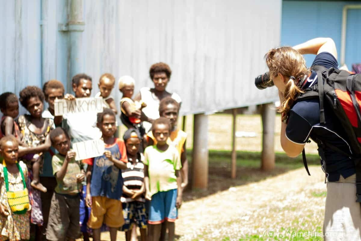 Photographer taking a photo of a group of children holding a "Thank You" sign