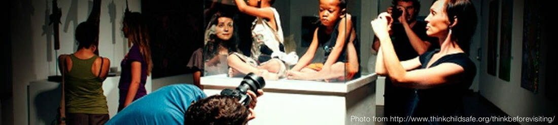 Visitors photographing children displayed in a glass case as an art exhibit, illustrating exploitative "orphan tourism