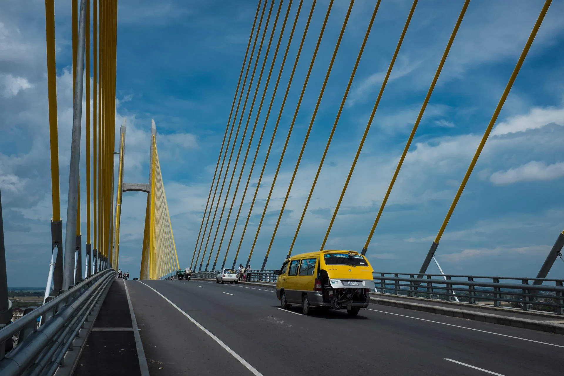 Bright yellow suspension cables stand out against the blue sky.